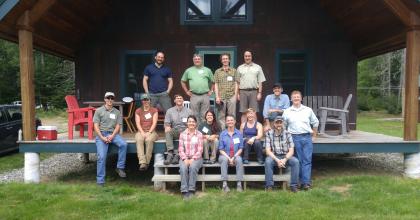 Fourteen scientists and managers sit on a porch at the Second College Grant