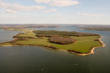 Aerial view of Newtowne Neck, a mosaic of forest, farmland, and beaches surrounded by ocean.