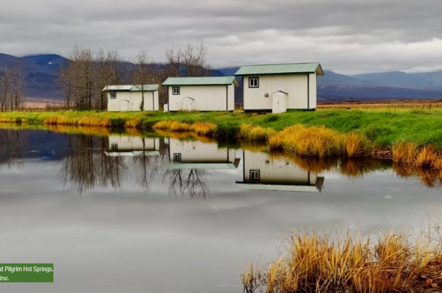 Picture of three small white cabins on the edge of a body of water at Pilgrim Hot Springs